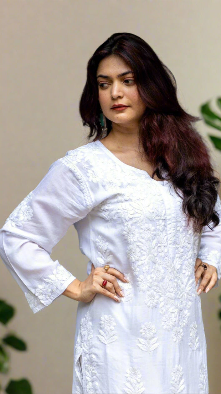 Woman wearing a white finely hand embroidered chikankari outfit, standing indoors