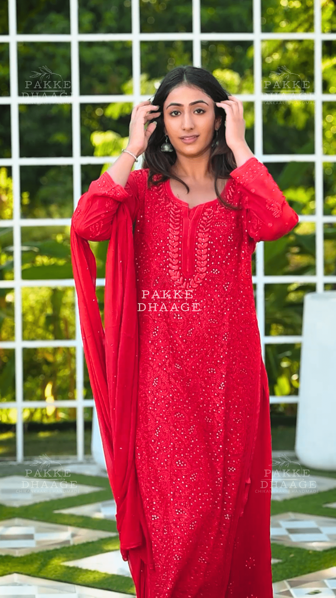 Woman wearing a red traditional chikankari outfit with mukaish work on hand-embroidery.