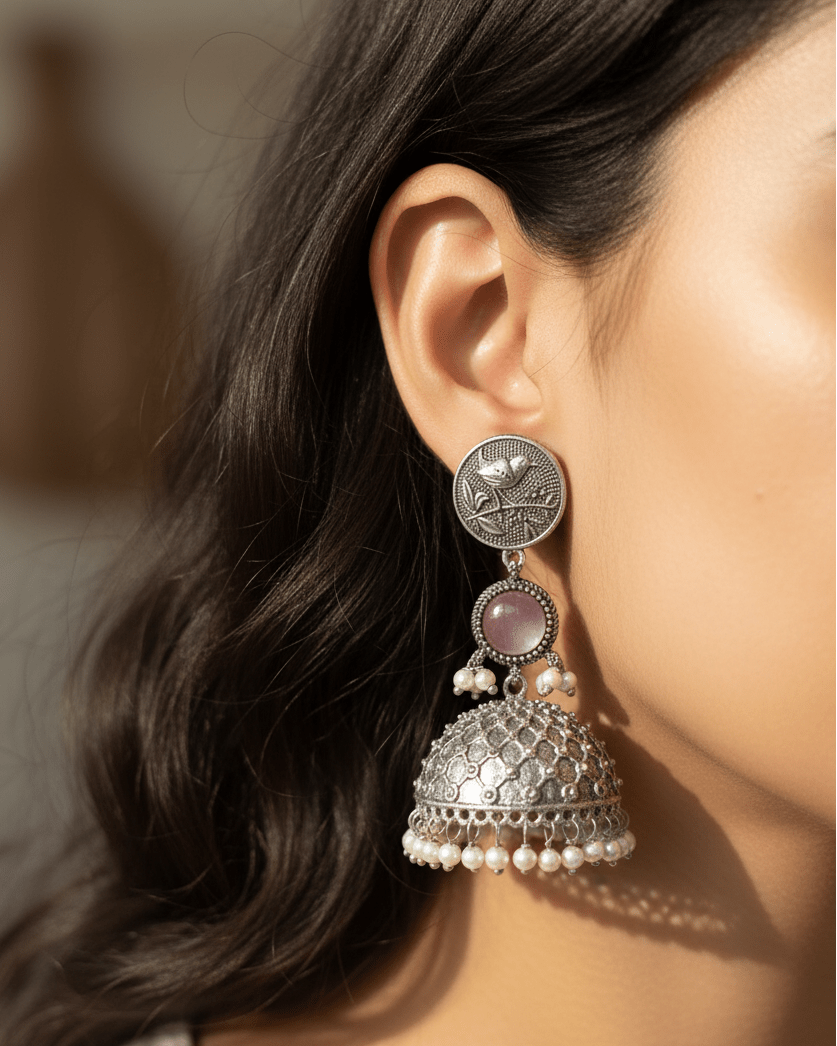 Close-up of a person wearing a silver and pearl earring with a pink stone.