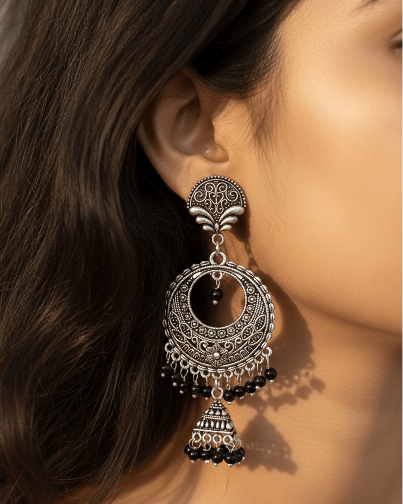 Close-up of a woman wearing an ornate oxidised silver earring with black beads.