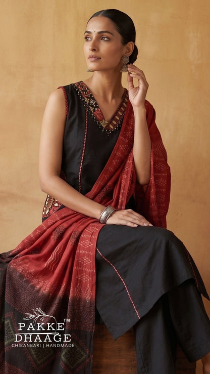 A woman models a black cotton chikankari kurta with a red patterned dupatta, set against a warm beige background. The brand logo 'PAKE DHAAGE' is visible in the bottom-left corner.