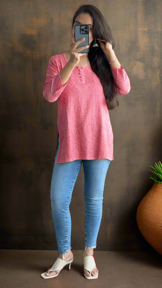 person wearing a chikankari handmade top paired with blue jeans in an indoor setting