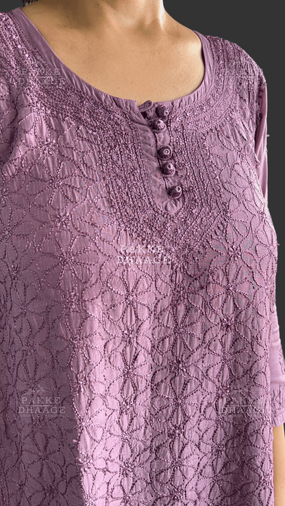 Close-up of a purple HAND-EMBROIDERED SHORT top with buttons on a blurred background