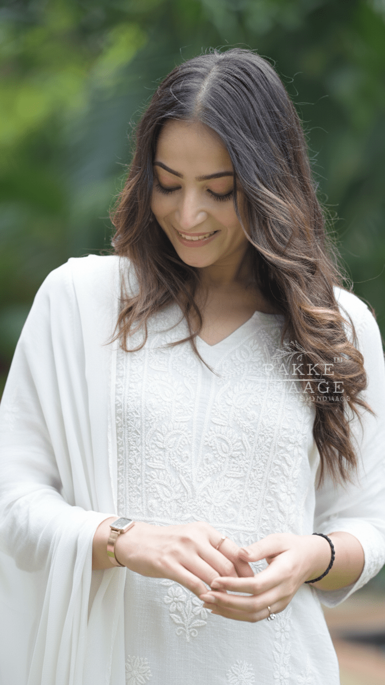 Woman in a white traditional chikankari kota doria suit with a blurred green background