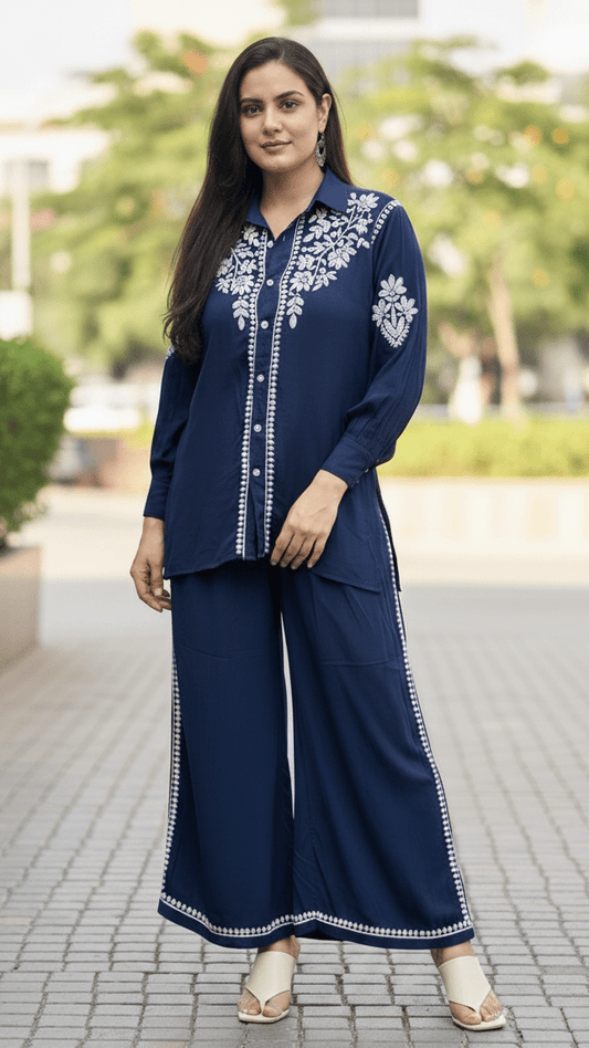 Woman wearing a navy blue traditional outfit with white embroidery outdoors.