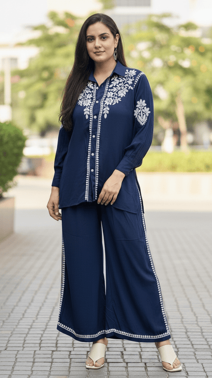 Woman wearing a navy blue traditional outfit with white embroidery outdoors.