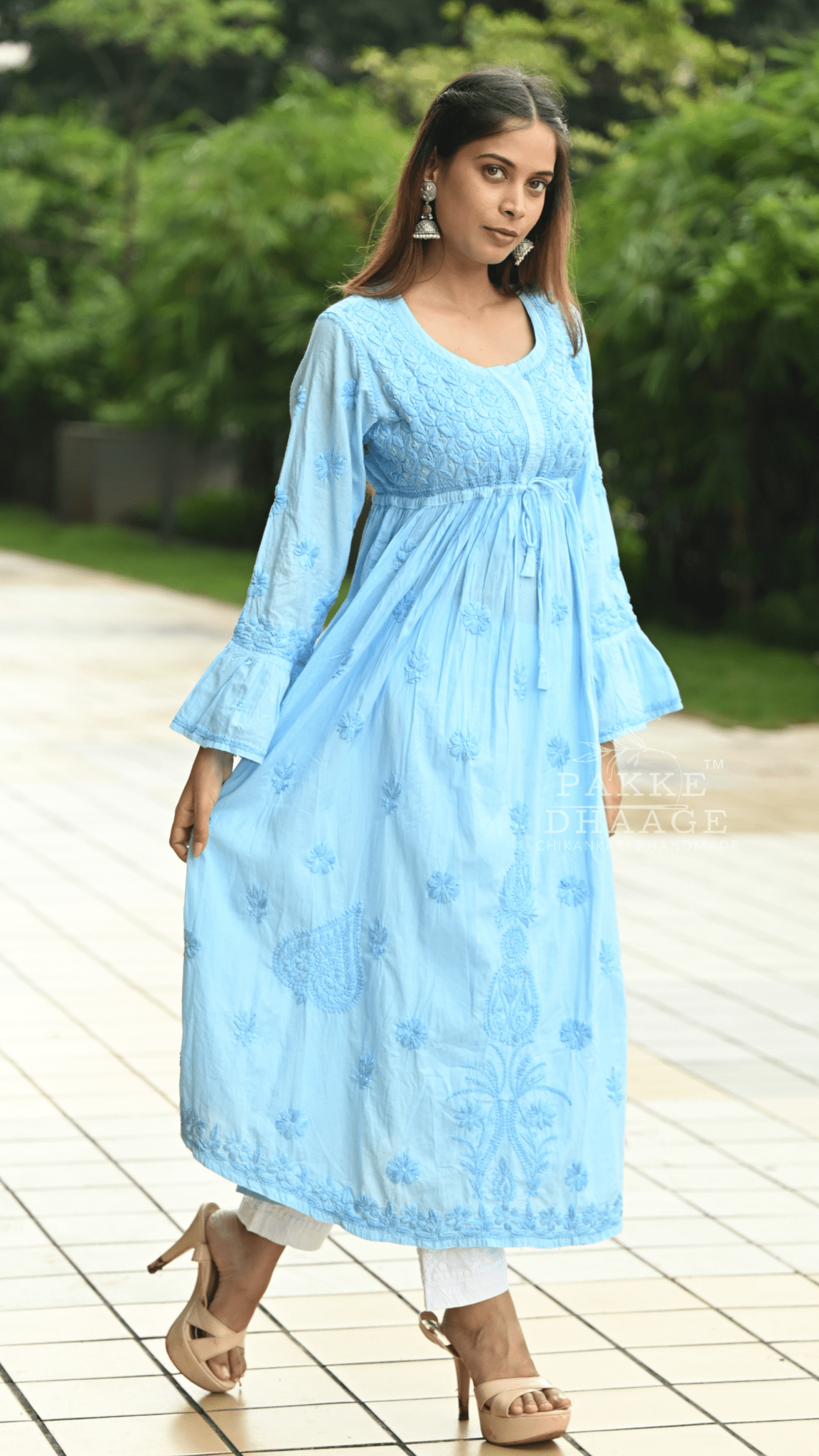 Woman wearing a light blue chikankari dress with floral patterns outdoors.