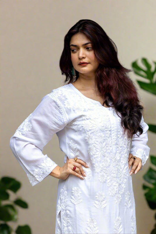 Woman wearing a white finely hand embroidered chikankari outfit, standing indoors