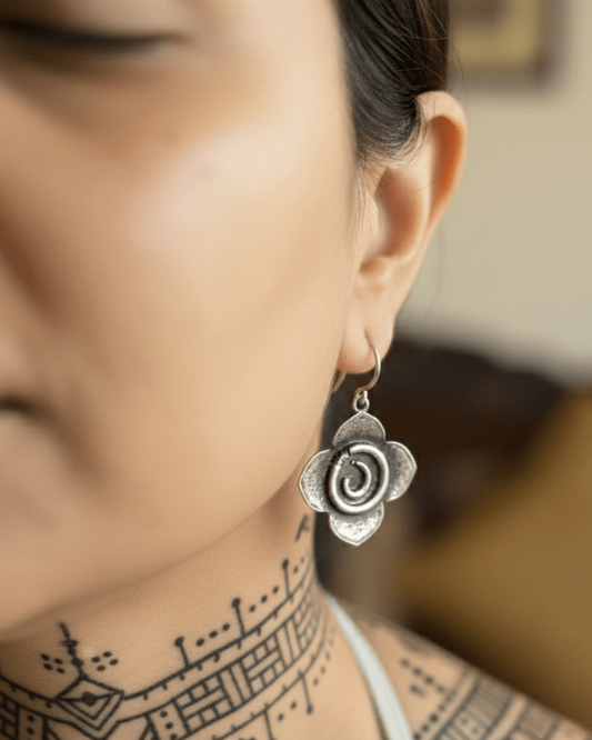 Close-up of a person wearing a silver floral earring with a blurred background