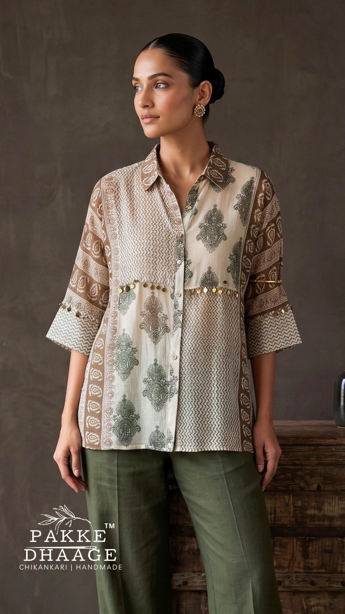 A woman modeling a beige and brown printed kurta with green leaf motifs and gold embroidery, paired with olive green trousers, set against a rustic brown background. The brand logo 'PAKKE DHAAGE' is visible in the bottom left corner.