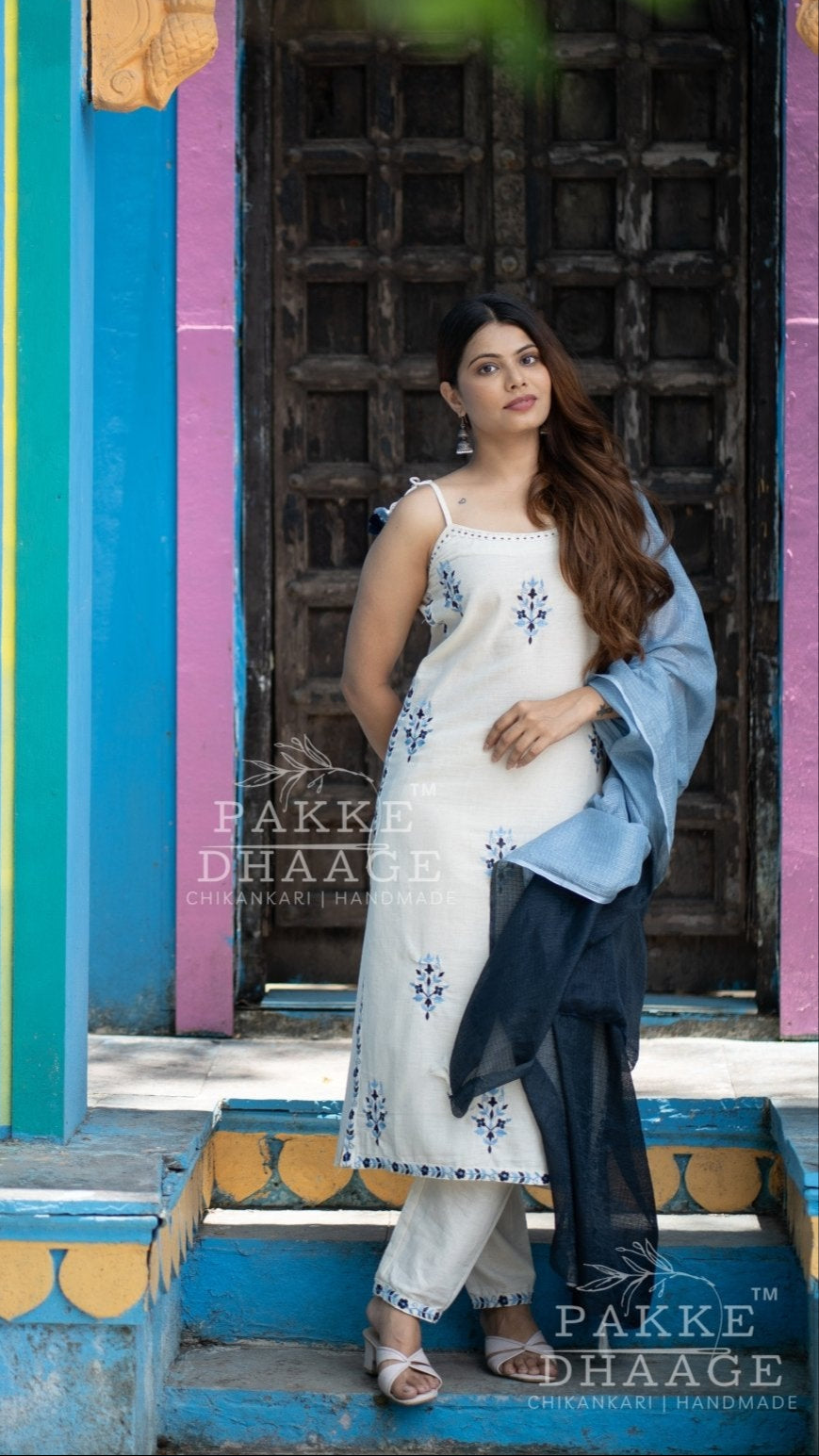 Woman in an elegant printed suit set standing in front of a colorful architectural background