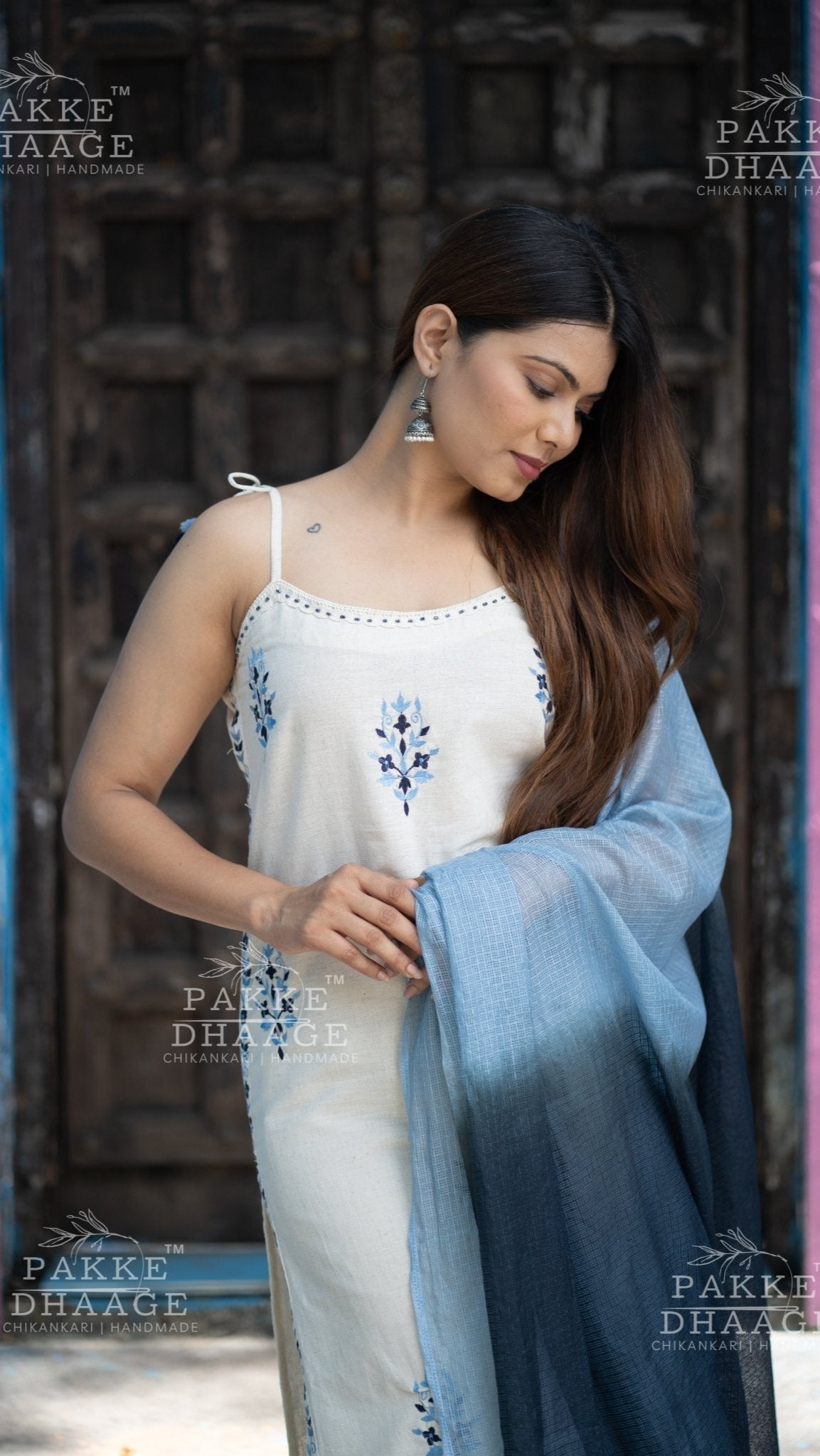 Woman in a white embroidered suit set holding an ombre blue dupatta with 'Pakke Dhaage' branding.