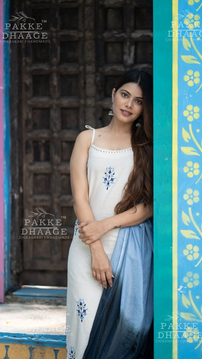 Woman in an embroidered suit set with floral design in front of a decorative door