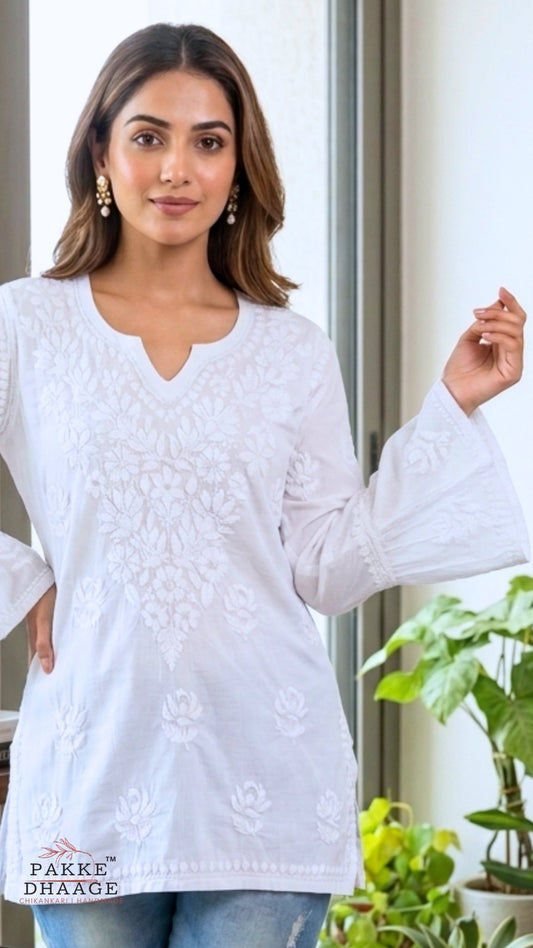 Woman wearing a white chikankari embroidered top with a blurred background