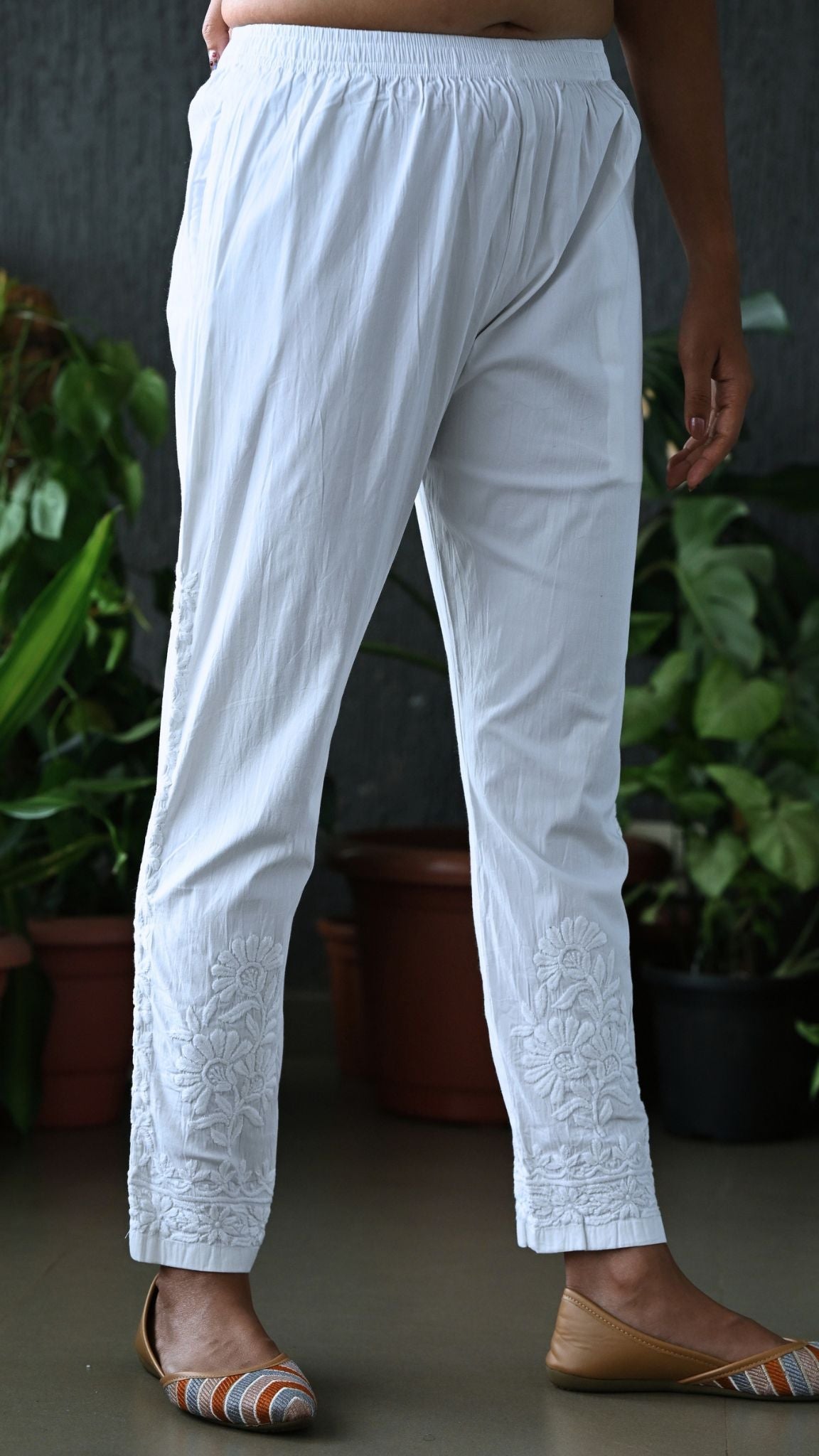 Side angle showing vertical floral vine Chikankari hand embroidery along the outer seam and ankle hem.
