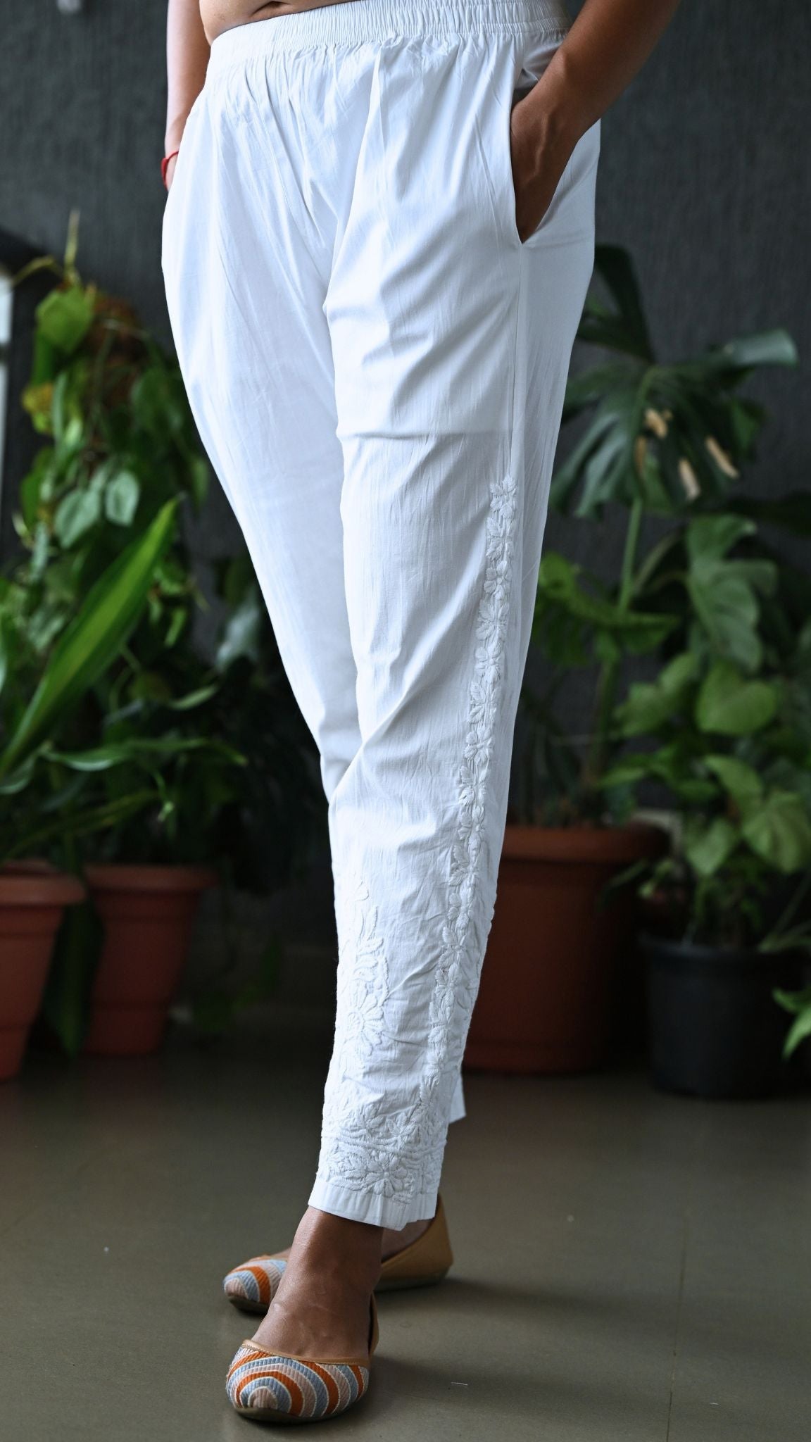 Detailed view of traditional Lucknowi Chikankari floral motifs and side pocket placement on white cotton trousers.