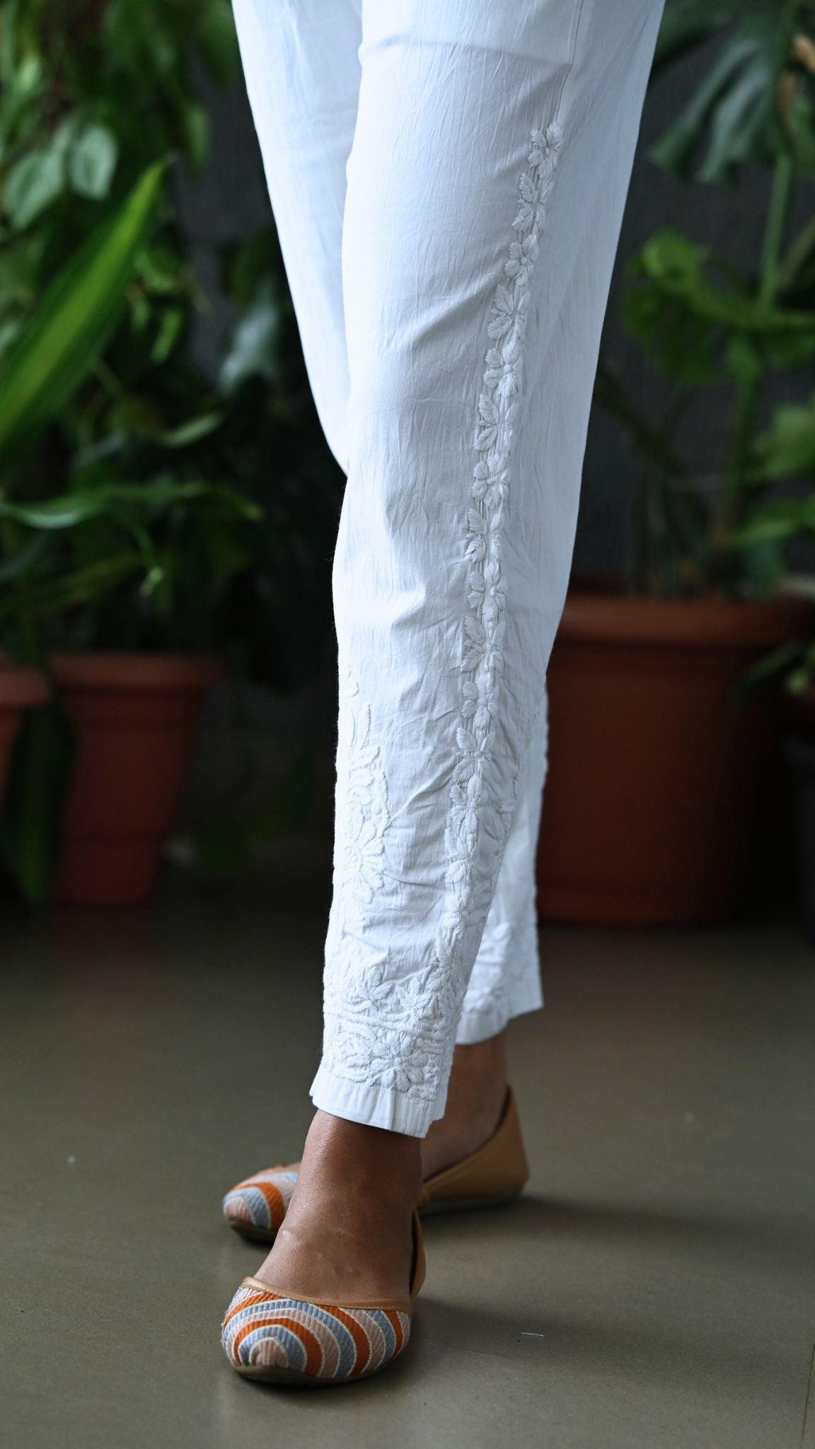 Side angle showing vertical floral vine Chikankari hand embroidery along the outer seam and ankle hem.