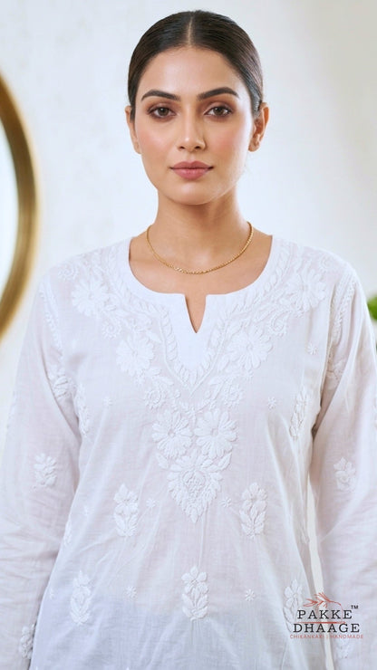 Close-up shot of a woman wearing a white chikankari embroidered outfit with a blurred background