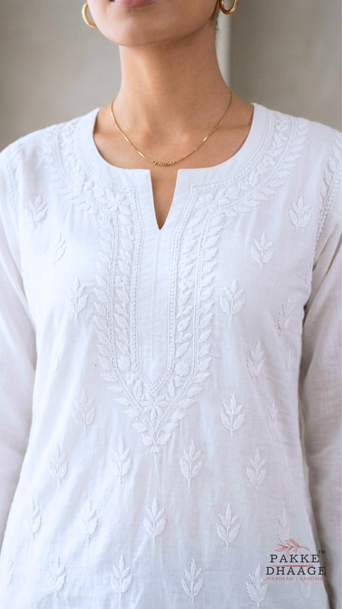 White chikankari embroidered top with a subtle pattern, worn by a person, on a neutral background.