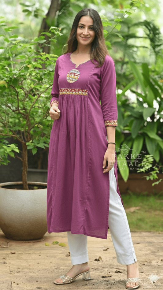Woman wearing a purple kurta with white pants in a garden setting