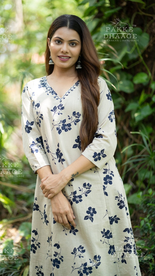 Woman wearing a off-white printed suit set with blue floral patterns standing in a natural setting.