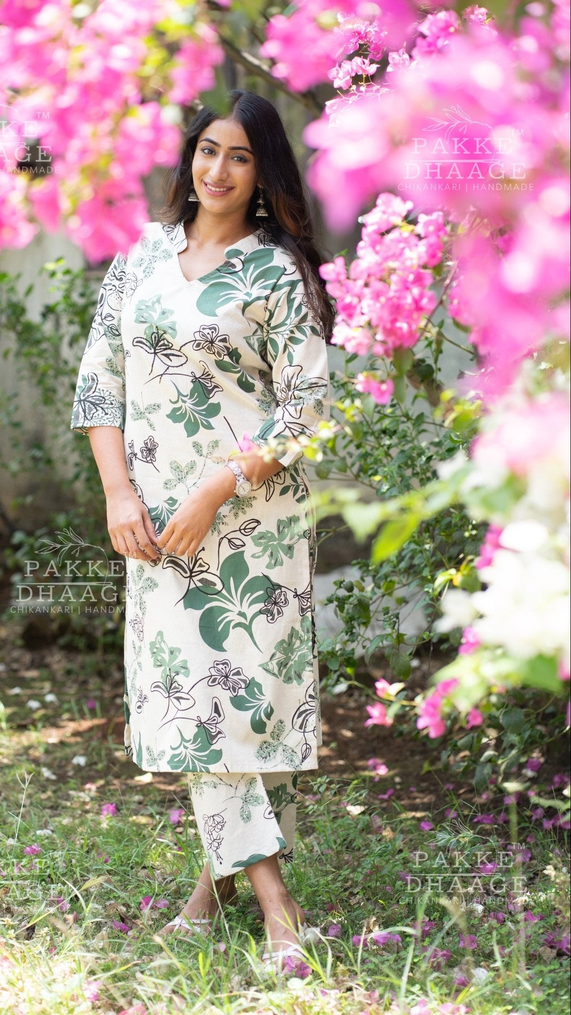 Woman in a printed floral ivory kurti set standing among pink flowers