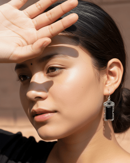 Woman with hand shielding her face, wearing a dangling handmade oxidized earring.