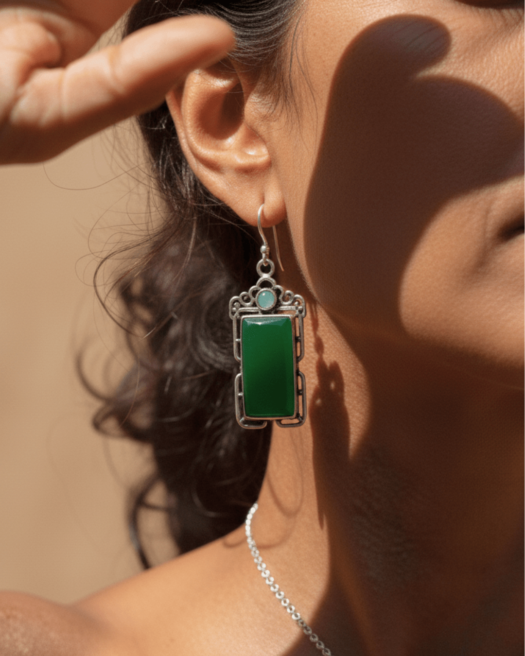 Close-up of a person wearing a green handmade oxidized earring with a silver frame.