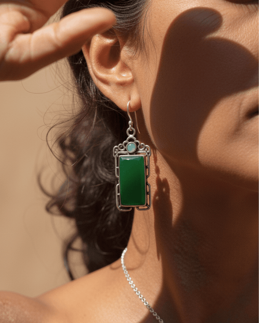Close-up of a person wearing a green handmade oxidized earring with a silver frame.