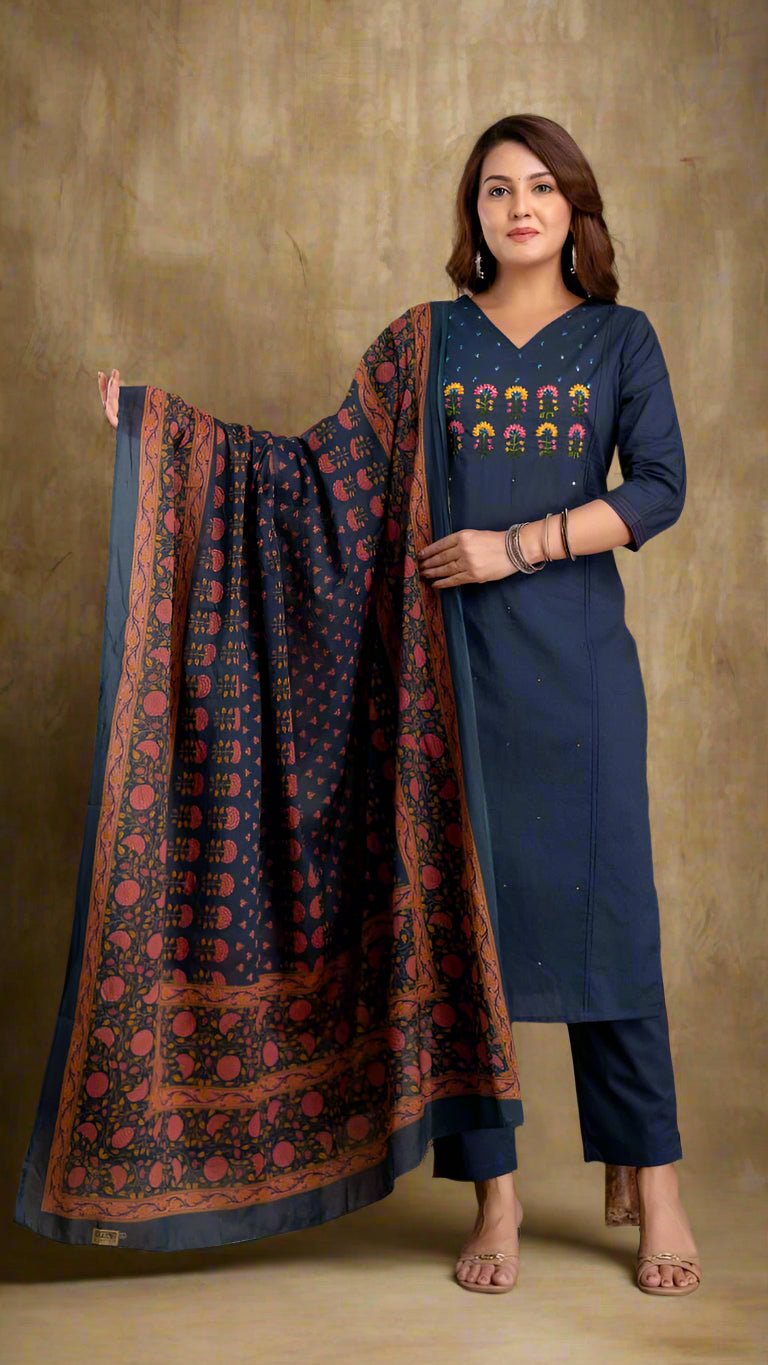Woman wearing a navy blue kurta with a patterned dupatta against a textured wall.