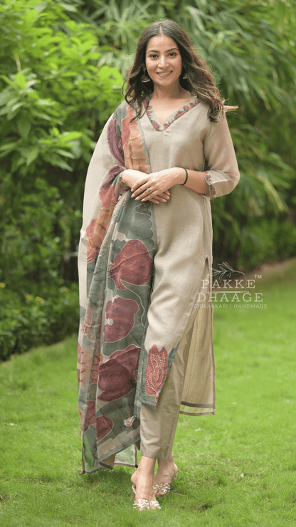 Woman in traditional suit set standing outdoors with greenery in the background