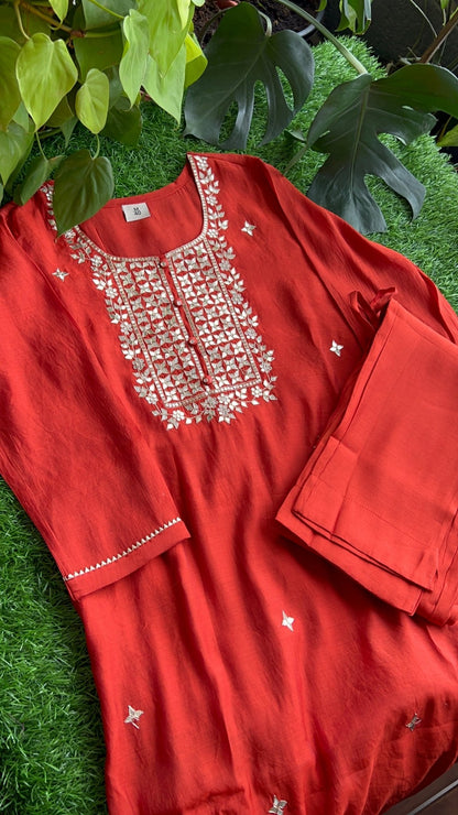 Red outfit with golden gota-patti work on a green grass background