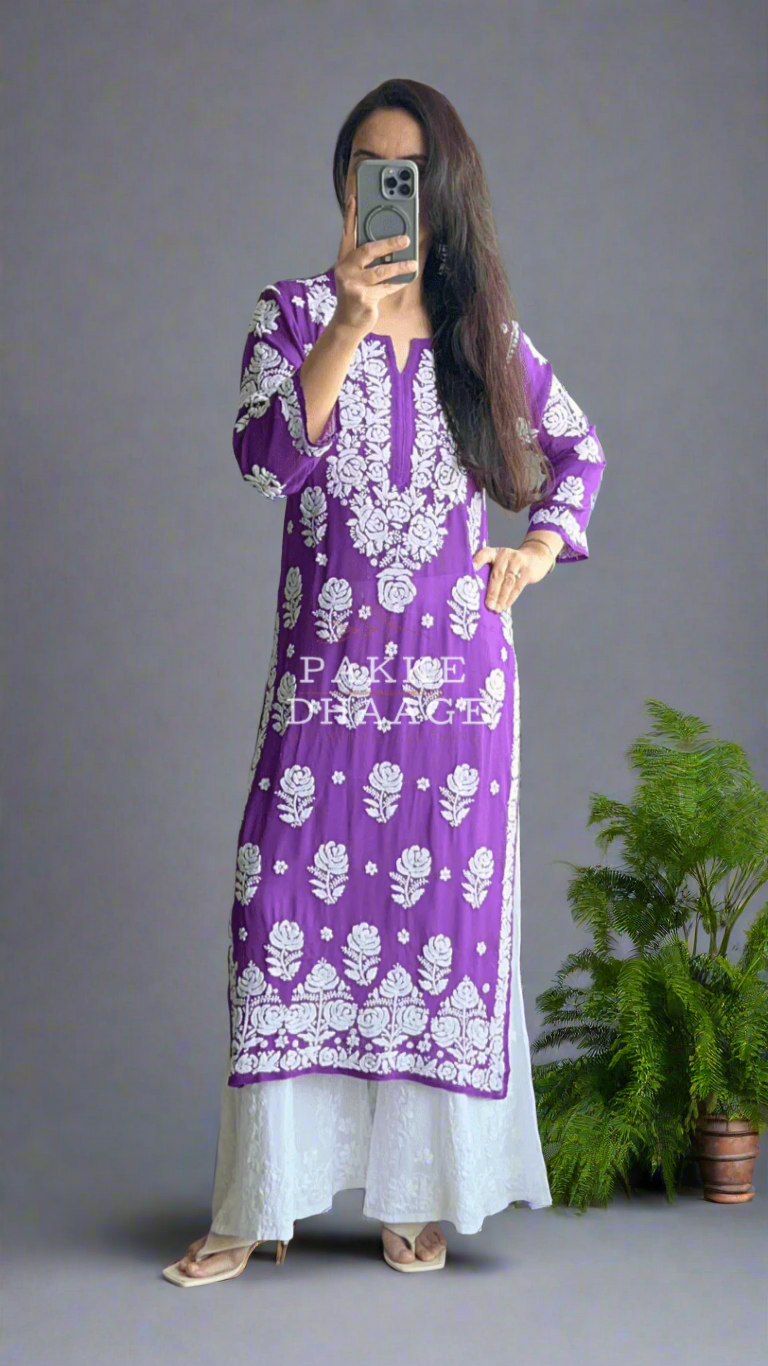 Person wearing a purple and white chikankari kurti in front of a mirror with plants around.