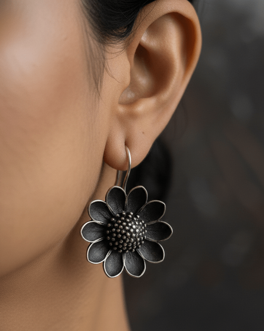 Close-up of a person wearing a floral earring with a dark background