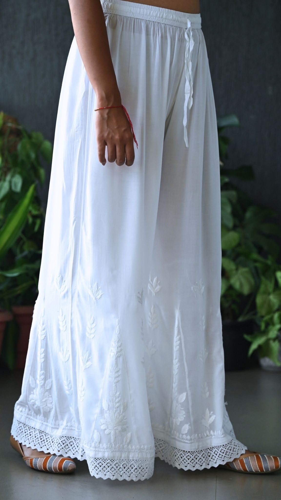 A person wearing a white embroidered wide-leg chikankari palazzo with Lace Detailing | Pakke Dhaage