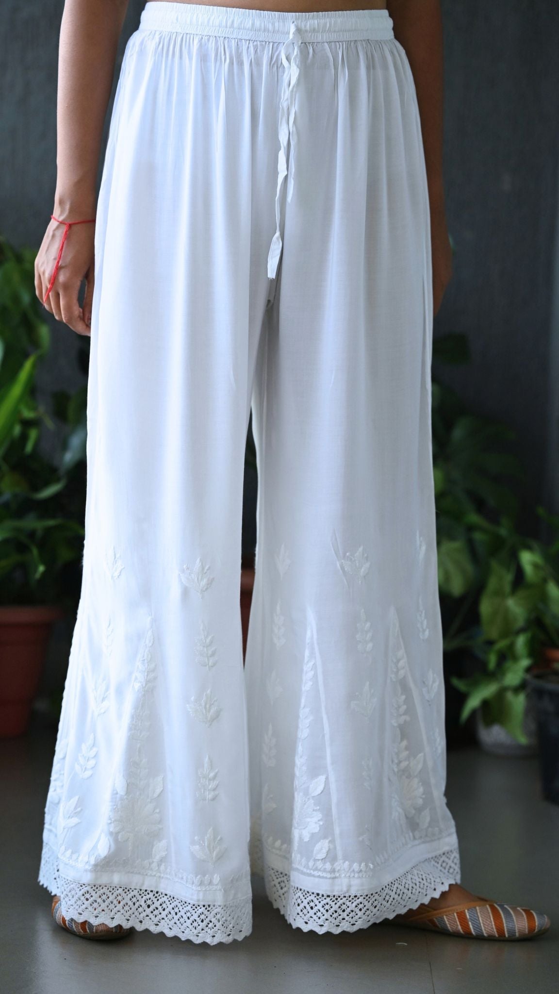 A person wearing a white embroidered wide-leg chikankari palazzo with Lace Detailing | Pakke Dhaage