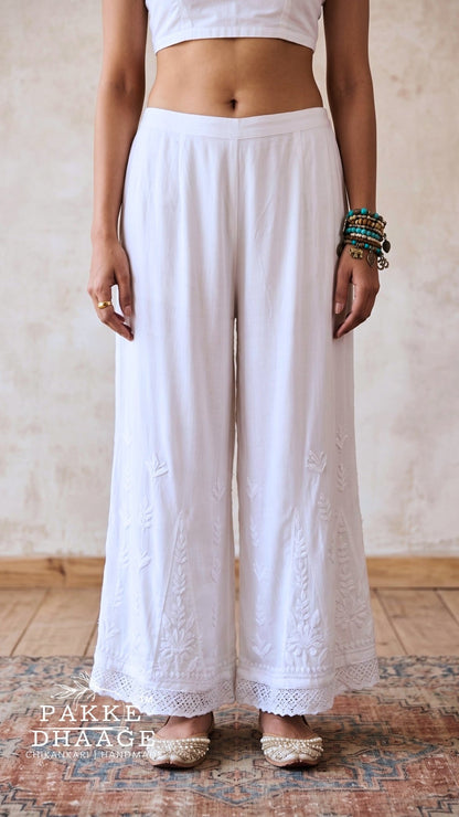 Person wearing white Chikankari lace palazzo by Pakke Dhaage, with a neutral background