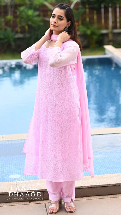 A woman wearing a light pink chikankari outfit with matching pants and a sheer dupatta, standing by a swimming pool. The brand name 'PAKKE DHAAGE' is visible as a watermark at the bottom left.