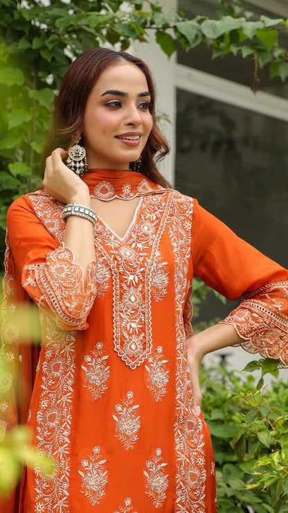 Woman wearing an orange embroidered dress with a green outdoor background