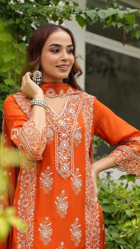Woman wearing an orange embroidered dress with a green outdoor background