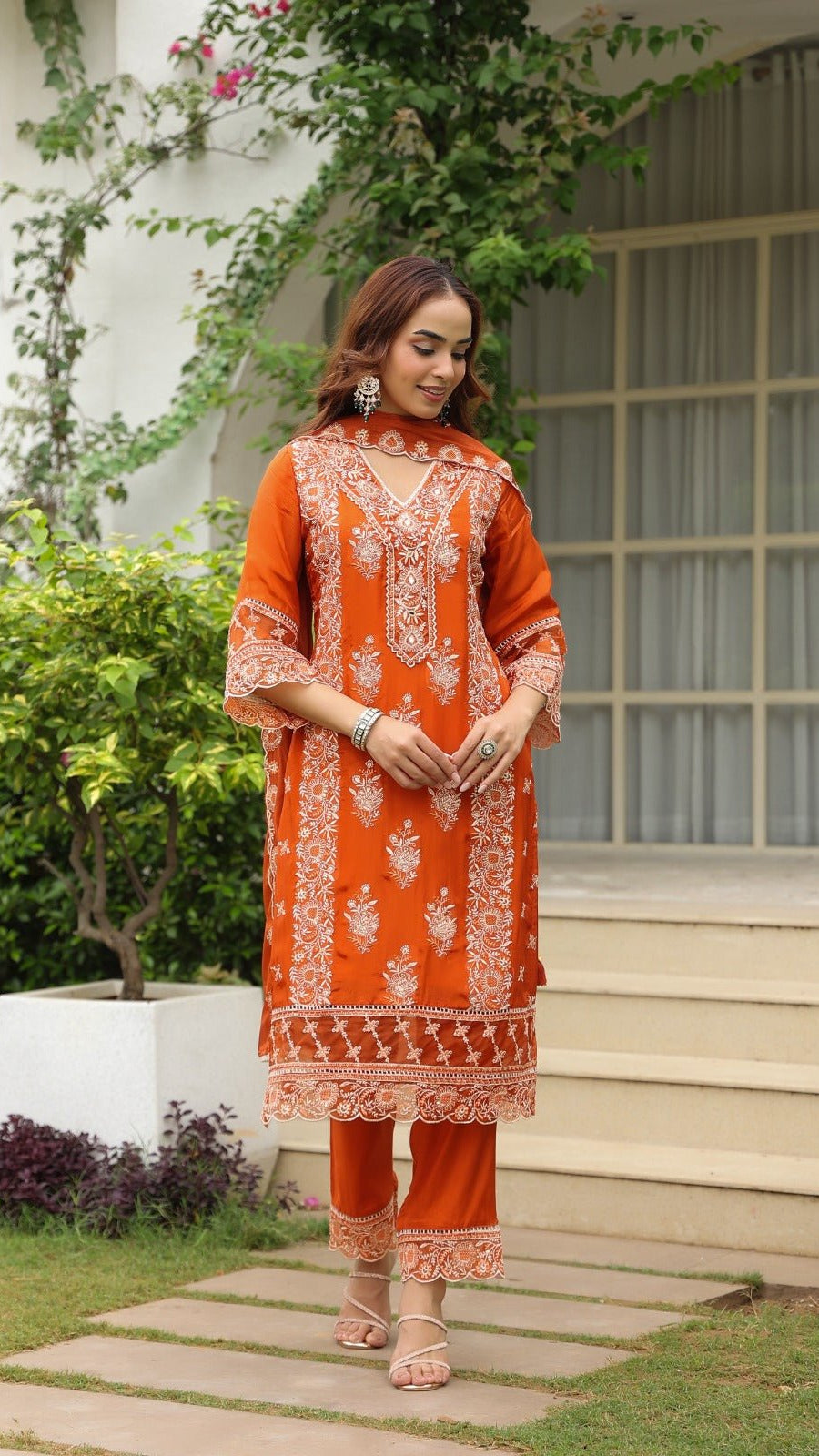 Woman wearing an orange embroidered outfit standing outdoors.
