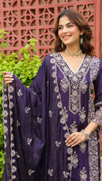 Woman wearing a purple embroidered outfit with a decorative background