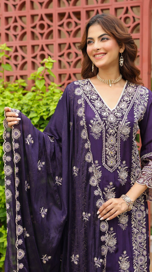 Woman wearing a purple embroidered outfit with a decorative background