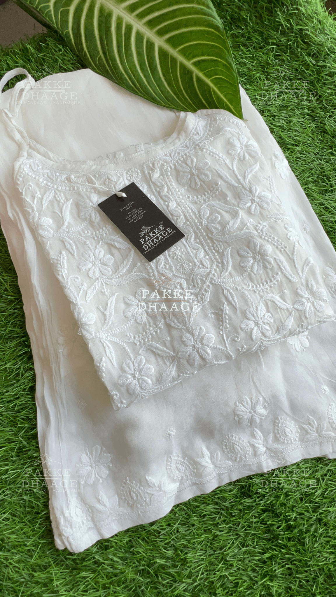 White handmade chikankari kurta with a Pakke Dhaage tag on a green grass background