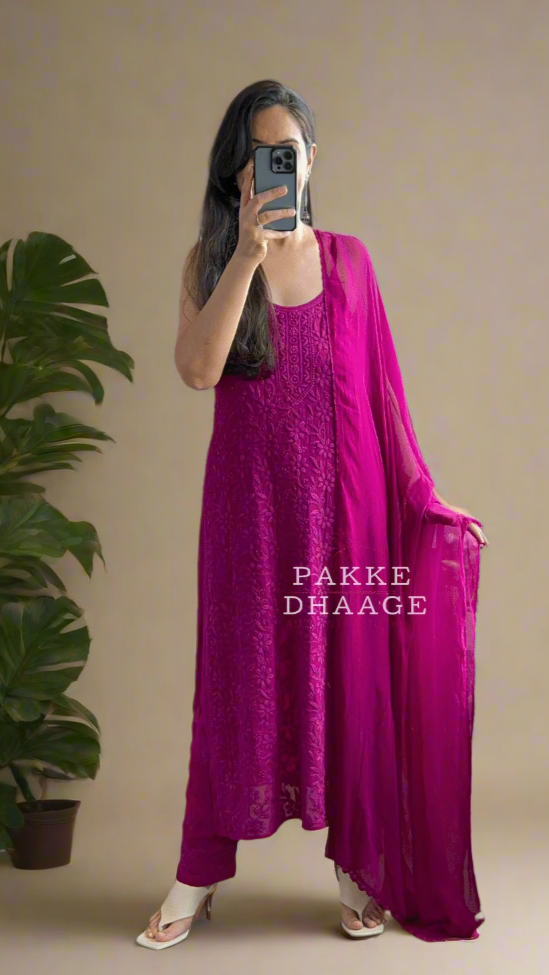 Person wearing a deep bright purple dress standing in front of a mirror with plants around.