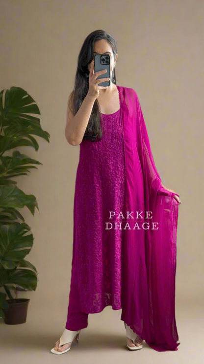 Person wearing a deep bright purple dress standing in front of a mirror with plants around.