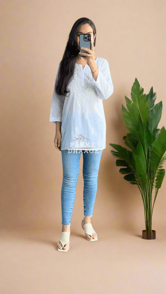 Person wearing a white chikankari top and  a light blue shirt and jeans.