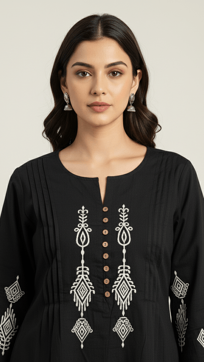 Woman wearing a black embroidered dress with a plain background