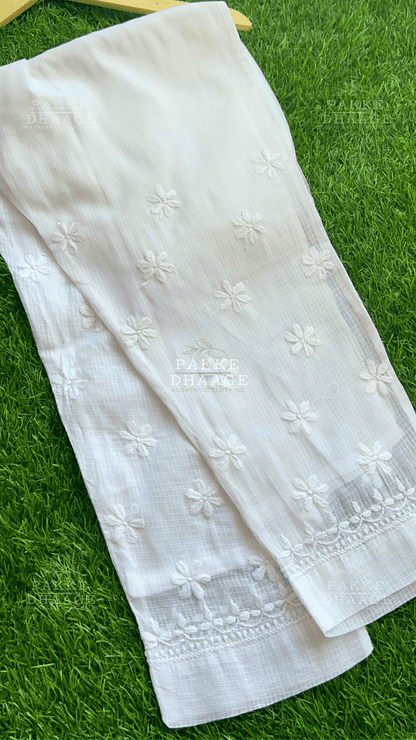 White embroidered chikankari pants in Kota Doria on a green grass background