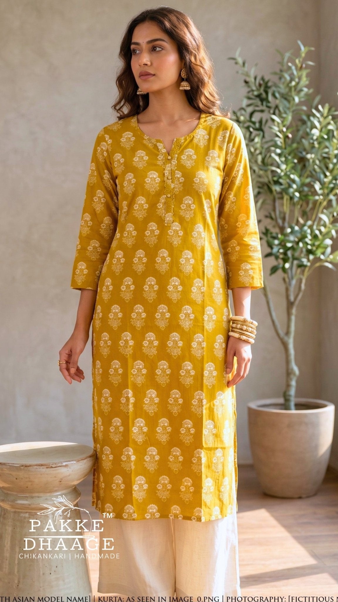 A woman modeling a mustard yellow kurta with white block prints, paired with cream trousers, in a styled indoor setting with a potted plant and rustic bowls. | Pakke Dhaage
